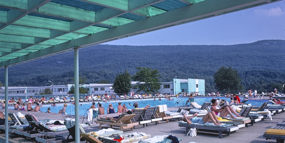 Vacationers sunbathe at Homowak pool, with the Catskill Mountains in the background. 