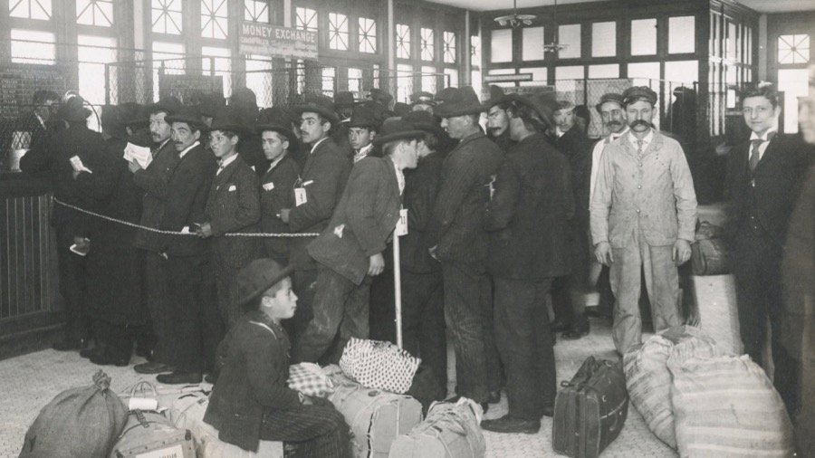 Black and white photo of men in line, luggage strewn about