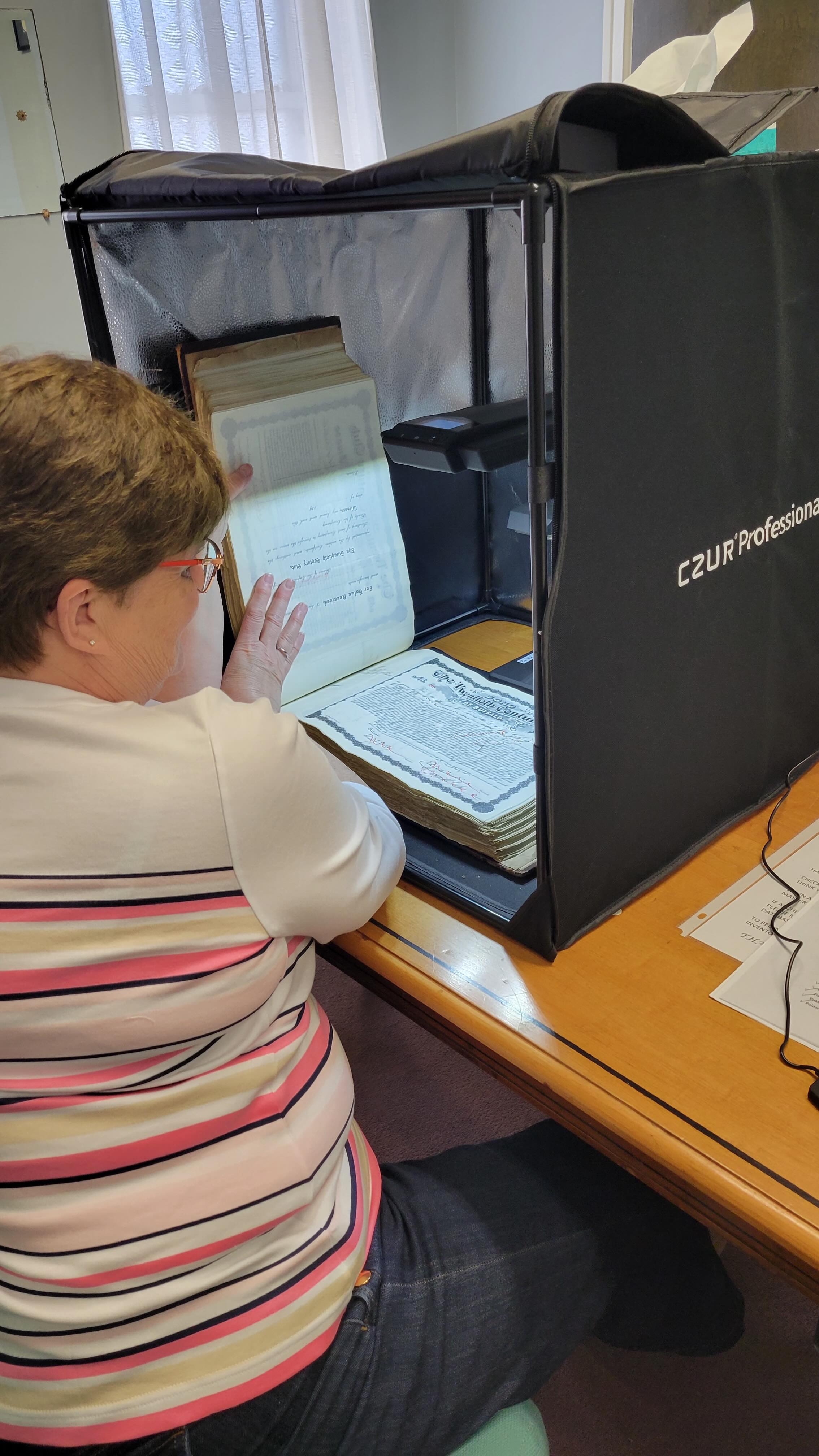Barbara Burns, member of the Archives Committee for the Twentieth Century Club of Buffalo, digitizes records of member bonds from the early 1900s.