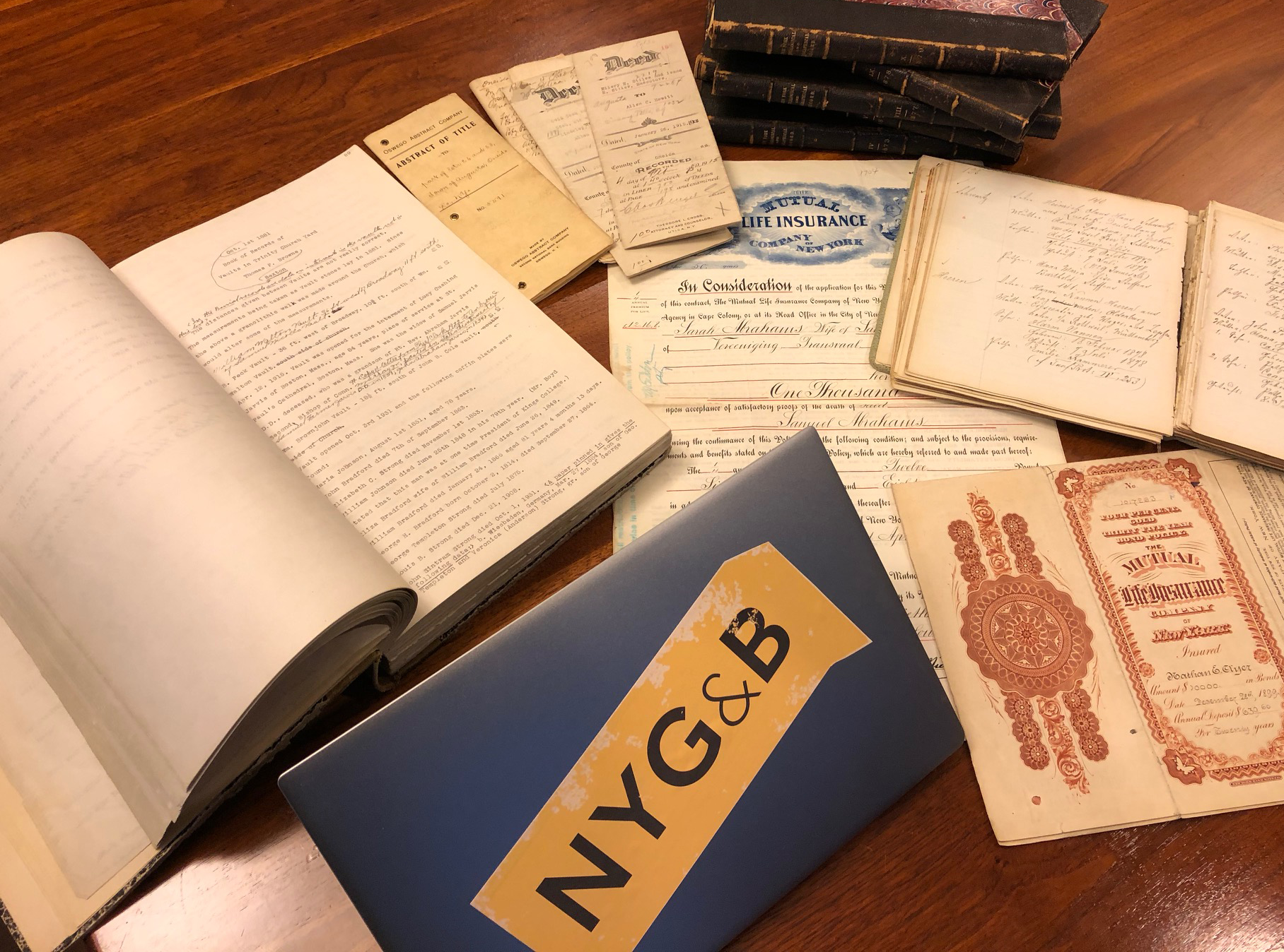 Genealogy documents and a laptop with an NYG&B logo