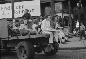 Children, recruited for farm work during the summer sit on the back of a truck. 
